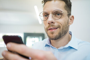 Porträt eines selbstbewussten Geschäftsmannes, der ein Mobiltelefon hält - MOEF02220