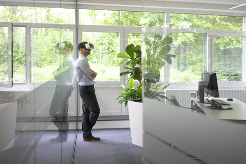 Businessman wearing VR glasses in office - MOEF02224