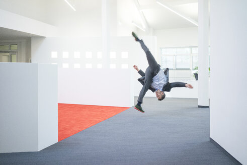 Geschäftsmann springt in der Luft auf dem Büroboden - MOEF02236