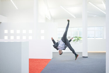 Businessman jumping mid-air on office floor - MOEF02237