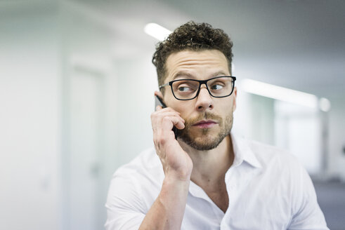 Porträt eines Geschäftsmannes am Handy im Büro - MOEF02249