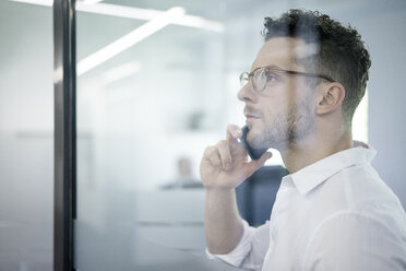 Porträt eines Geschäftsmannes am Handy im Büro - MOEF02252