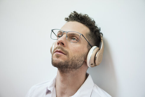 Porträt eines Geschäftsmannes, der mit Kopfhörern Musik hört - MOEF02256