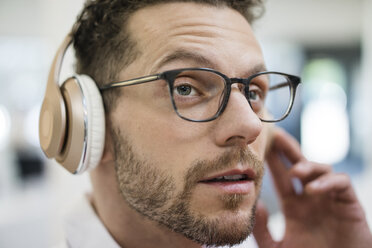 Porträt eines Geschäftsmannes, der mit Kopfhörern Musik hört - MOEF02262
