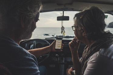 Senior couple traveling in a vintage van, using smartphone - SIPF01983