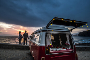 Älteres Paar, das in einem Oldtimer-Van unterwegs ist und den Sonnenuntergang am Meer beobachtet - SIPF01986