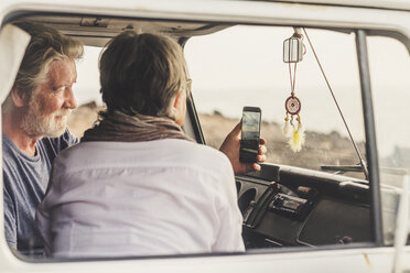 Älteres Paar, das in einem Oldtimer-Van unterwegs ist und ein Smartphone benutzt - SIPF01990