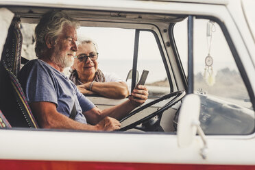 Älteres Paar, das in einem Oldtimer-Van unterwegs ist und ein Smartphone benutzt - SIPF01991