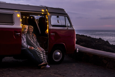 Älteres Paar, das in einem Oldtimer-Van unterwegs ist und den Sonnenuntergang am Meer beobachtet - SIPF02030