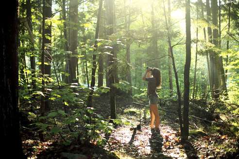 Mädchen schaut durch ein Fernglas im Wald - BLEF05878