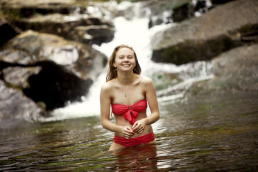 Caucasian teenage girl standing in river near waterfall - BLEF05901