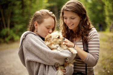 Girls petting puppy in forest - BLEF05904