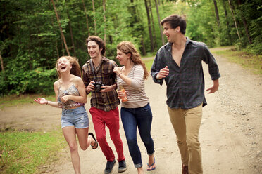 Friends running on dirt path in forest - BLEF05906