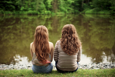 Rückansicht von Mädchen, die am See sitzen - BLEF05910