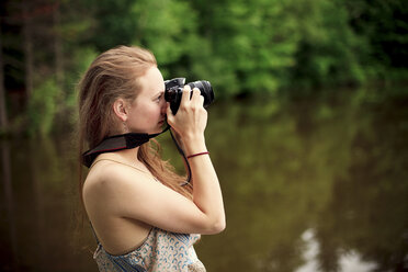 Caucasian teenage girl photographing lake - BLEF05913