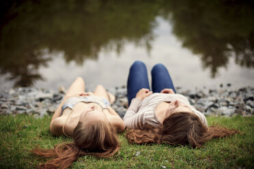 Rear view of girls laying near lake - BLEF05914