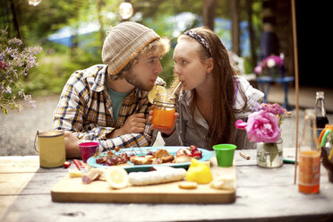 Couple sharing soda at picnic table in forest - BLEF05923