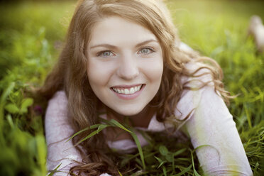 Smiling woman laying in rural field - BLEF05998