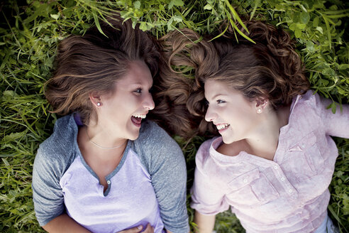 Lachende kaukasische Frauen, die im Gras liegen - BLEF06000
