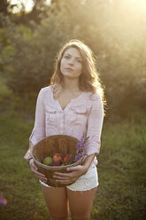 Woman carrying bucket of apples in field - BLEF06004