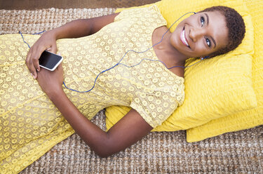 Schwarze Frau, die auf dem Teppich einen mp3-Player hört - BLEF06052