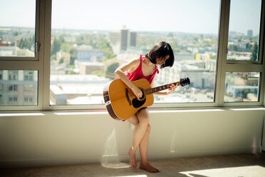 Asiatische Frau spielt Gitarre im Fenster - BLEF06058