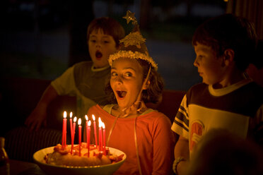 Lachendes Mädchen, das Kerzen auf einem Geburtstagskuchen ausbläst - BLEF06065
