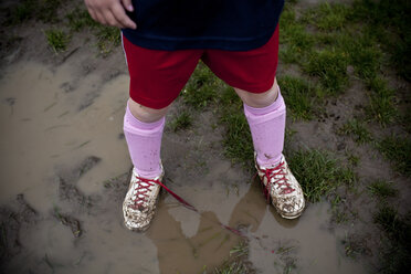 Girl wearing sneakers in mud puddle - BLEF06068