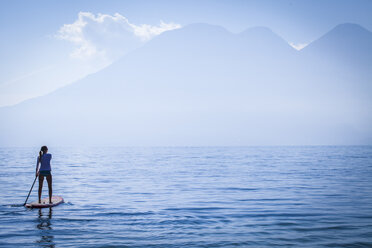 Girl standing on paddleboard in remote lake - BLEF06071