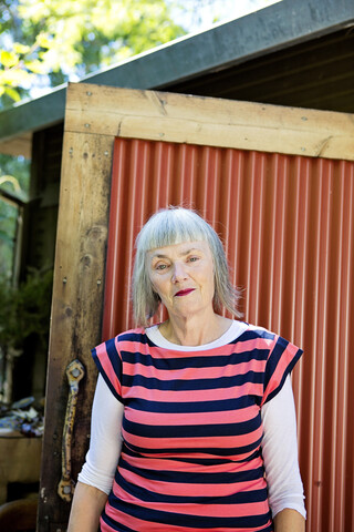 Ältere kaukasische Frau steht im Hinterhof, lizenzfreies Stockfoto