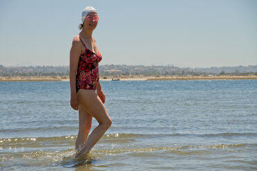 Kaukasische Frau, die in den Wellen am Strand spazieren geht - BLEF06103