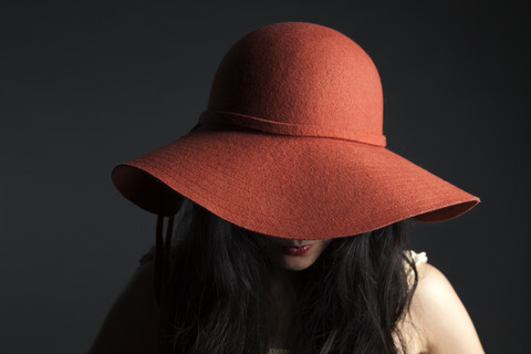 Asiatische Frau versteckt sich hinter rotem Hut, lizenzfreies Stockfoto