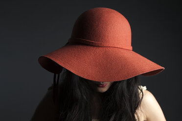 Asian woman hiding behind red hat - BLEF06132