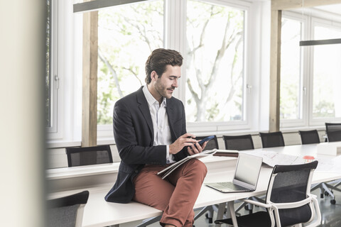 Junger Geschäftsmann sitzt im Sitzungssaal und bereitet sich auf eine Präsentation vor, lizenzfreies Stockfoto