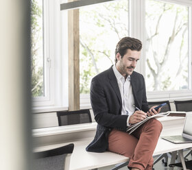 Young businessman sitting in boardroom, preparing for presentation - UUF17696