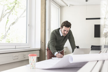 Junger Architekt arbeitet an einem Entwurf in einem hellen Büro - UUF17719