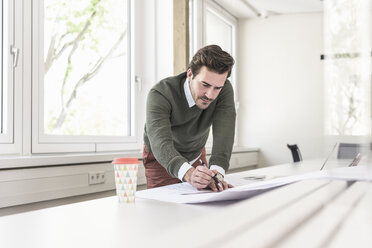 Junger Architekt arbeitet an einem Entwurf in einem hellen Büro - UUF17723