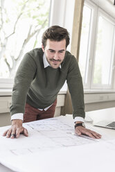 Young architect working on blueprint in bright office - UUF17724