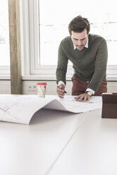 Young architect working on blueprint in bright office - UUF17726