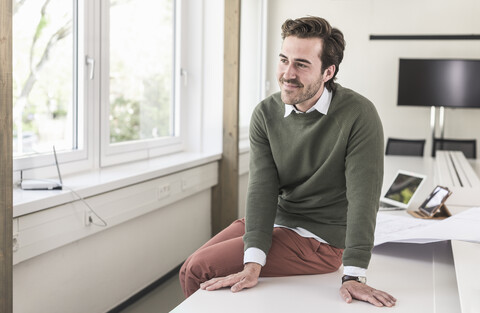 Erfolgreicher, junger Geschäftsmann sitzt im Sitzungssaal, lizenzfreies Stockfoto