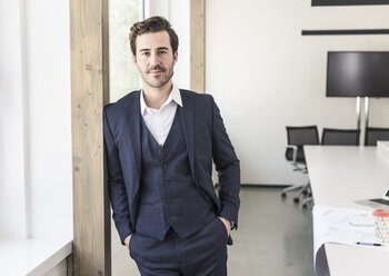 Confident businessman standing in boardroom - UUF17737