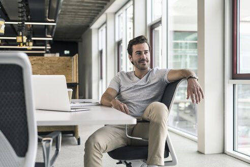 Junger Geschäftsmann arbeitet entspannt in einem modernen Büro und denkt nach - UUF17810