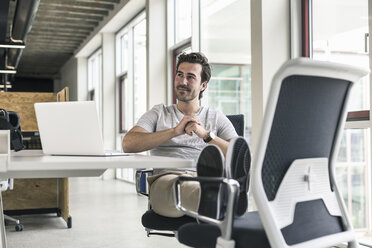 Young businessman working relaxed in modern office, thinking - UUF17812