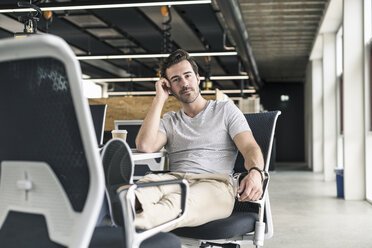 Junger Geschäftsmann arbeitet entspannt in einem modernen Büro und denkt nach - UUF17813