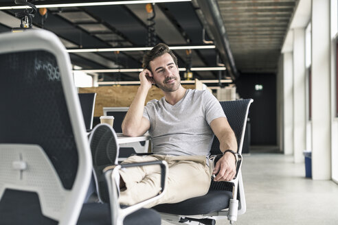 Junger Geschäftsmann arbeitet entspannt in einem modernen Büro und denkt nach - UUF17814