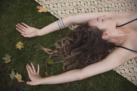 Frau liegt auf einer Decke im Gras, lizenzfreies Stockfoto