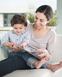 Smiling mother reading to son on sofa - BLEF06201