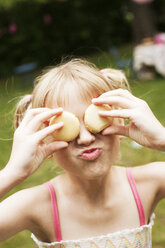 Close up of girl holding cookies over eyes in backyard - BLEF06226