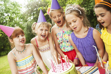 Girls admiring cake at birthday party outdoors - BLEF06237