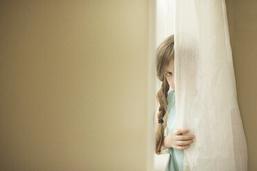 Shy Caucasian girl peeking around curtain - BLEF06244